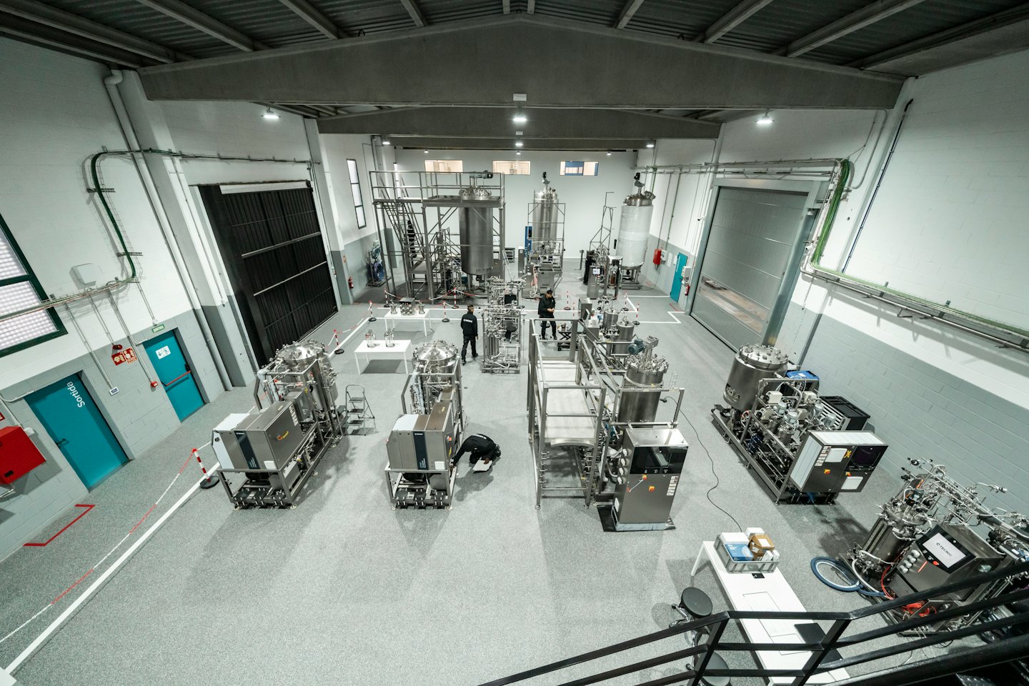 Deux hommes travaillent près de bioréacteurs dans un grand laboratoire moderne.