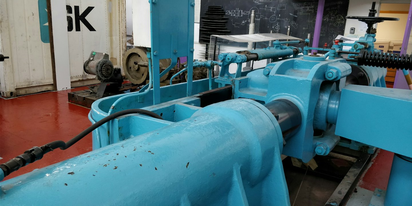Une machine industrielle bleue est posée sur un sol d'usine rouge.